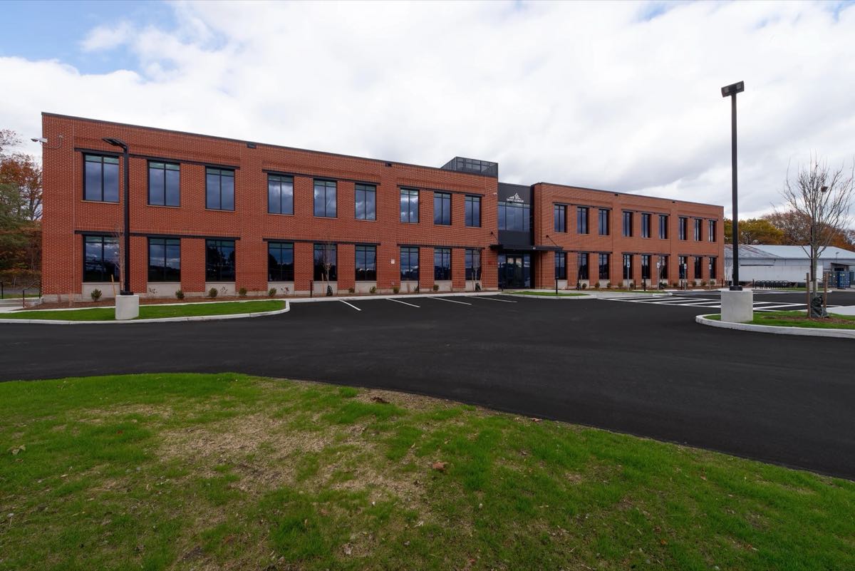 The Saint-Gobain facility in Worcester, Massachusetts — a two-story brick building fronting a freshly paved lot.