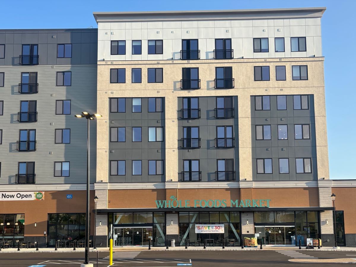 The Whole Foods Market storefront on Via Toscana in Salem, New Hampshire, beneath the finished upper floors of the building above it.